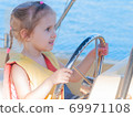 beautiful three-year-old girl at the helm of a boat on a clear day 69971108