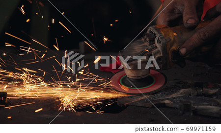 Professional mechanic is cutting steel metal. 69971159