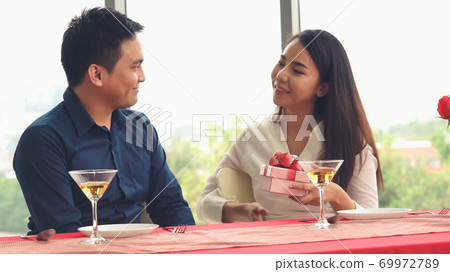 Romantic couple giving gift to lover at restaurant 69972789