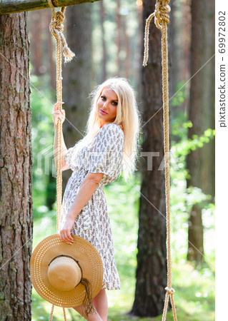 Blond woman with slender beautiful naked legs posing with on a rope swing 69972802