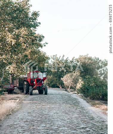 A red tractor stands by the road in the countryside. A man with a foot stands near a tractor A red tractor stands by the road in the countryside. A man with a foot stands near a tractor 69973255