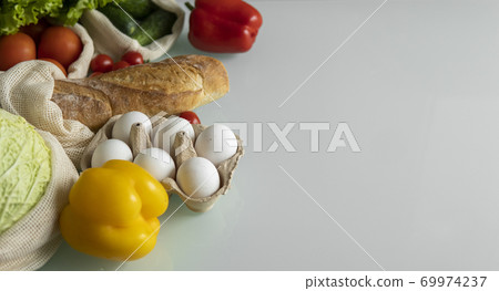 Vegetables, fruits, eggs in reusable eco cotton bags on table. Zero waste shopping concept. Plastic free items. Multi-use, reuse, recycle. Eco friendly canvas grocery bag with tomatoes, pepper, bread. 69974237