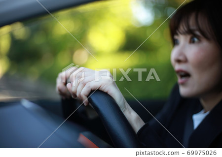 A woman with a surprised expression while driving 69975026