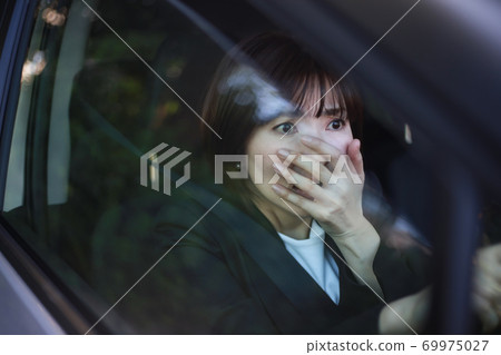 A woman with a surprised expression while driving A woman with a surprised expression while driving 69975027