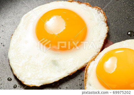 Fried egg baked in a frying pan. 69975202