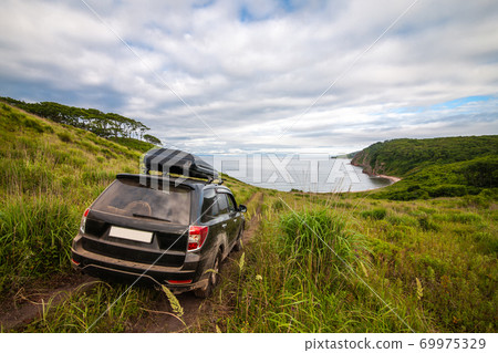 Black Subaru Forester with rooftop box on the road way down to the sea Black Subaru Forester with rooftop box on the road way down to the sea 69975329