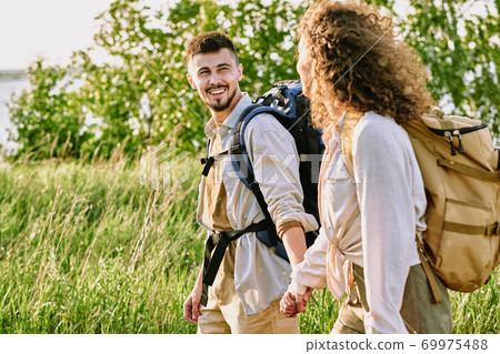 Positive couple holding hands during hike Positive couple holding hands during hike 69975488