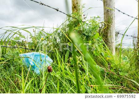 Face mask trash in the green during pandemic 69975592