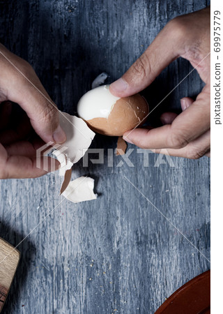 man removing the eggshell of a boiled egg 69975779