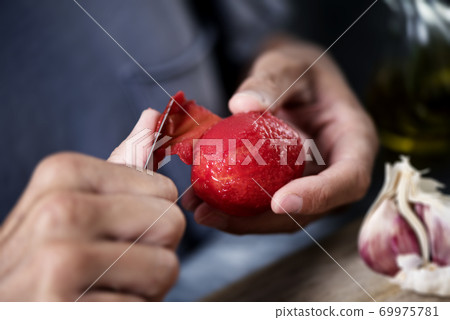 man peeling a scalded tomato 69975781