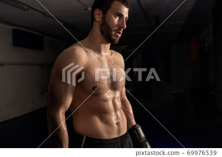 Boxer in boxing gloves on a black background after training 69976539