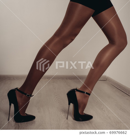 Slender female legs in stockings and a fetish shoe with extremely high heels. Slender female legs in stockings and a fetish shoe with extremely high heels. 69976662