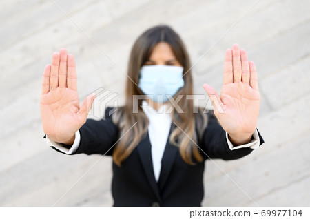 Coronavirus concept. Woman wearing mask for protection from disease, shows stop gesture with hands Coronavirus concept. Woman wearing mask for protection from disease, shows stop gesture with hands 69977104