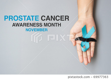 November Prostate Cancer Awareness month, adult Man holding light Blue Ribbon with mustache for supporting people living and illness. Healthcare, International men, Father and World cancer day concept 69977363