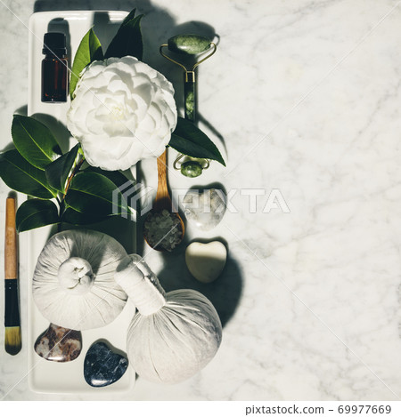 Flat lay composition with spring camelia flower and various beauty care products on white marble table Flat lay composition with spring camelia flower and various beauty care products on white marble table 69977669