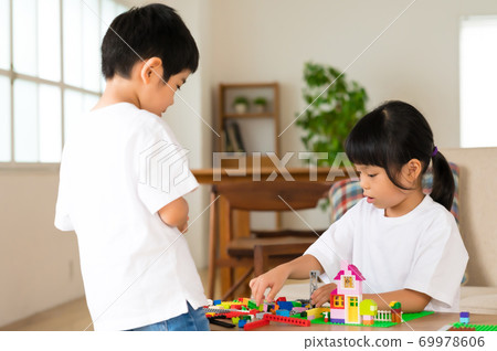 Siblings playing blocks at the living room table Siblings playing blocks at the living room table 69978606