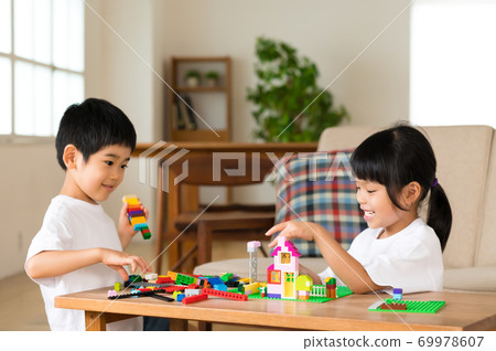 Siblings playing blocks at the living room table Siblings playing blocks at the living room table 69978607