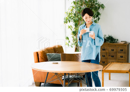 Women's living room standing smartphone coffee 69979305