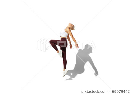 Beautiful young female athlete practicing on white studio background with shadow Beautiful young female athlete practicing on white studio background with shadow 69979442