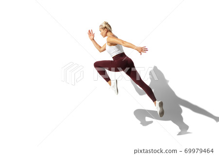 Beautiful young female athlete practicing on white studio background with shadow Beautiful young female athlete practicing on white studio background with shadow 69979464
