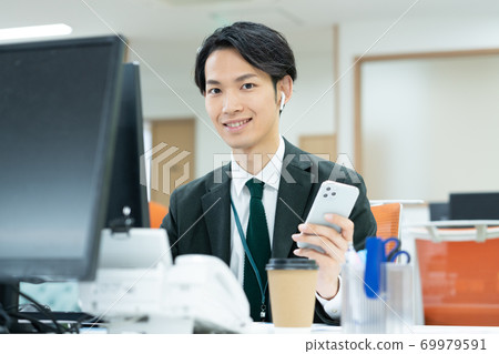 Smiling young business man working in the office Smiling young business man working in the office 69979591