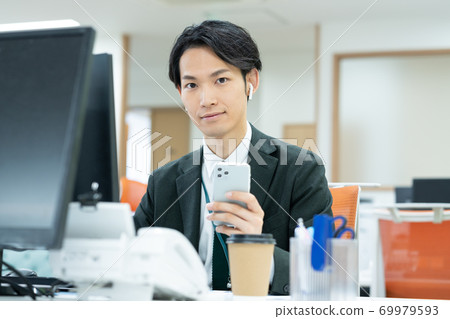Smiling young business man working in the office Smiling young business man working in the office 69979593