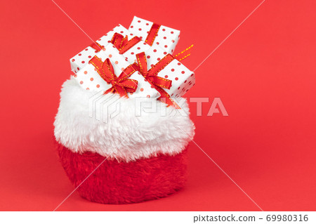 Heaps of christmas gifts in Santa Claus sack wrapped in gift paper polka with festive ribbon on red background with copy space. Heaps of christmas gifts in Santa Claus sack wrapped in gift paper polka with festive ribbon on red background with copy space. 69980316