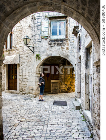 Female tourist on a medieval stone street in Split, Croatia 69980436
