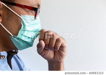 The young man has headache coughing and sneezing which is caused by the infection of the COVID-19 virus or the CORONA virus By wearing a mask to prevent the germs from spreading to those around you, H 69981323