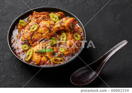 A Chicken Patiala in black bowl on dark slate table top. Murg Patiala is indian cuisine curry dish A Chicken Patiala in black bowl on dark slate table top. Murg Patiala is indian cuisine curry dish 69981554