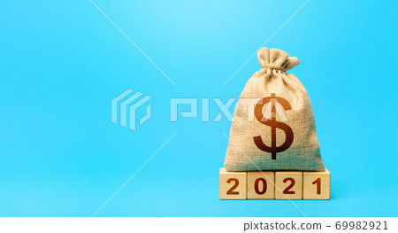 Dollar money bag and blocks 2021. Budget planning for next year. Beginning of new decade. Business plans and development prospects, trends and challenges. Revenues expenses, investment and financing. Dollar money bag and blocks 2021. Budget planning for next year. Beginning of new decade. Business plans and development prospects, trends and challenges. Revenues expenses, investment and financing. 69982921