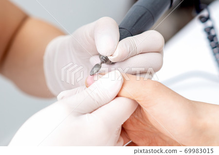 Manicure master uses an electric nail machine Manicure master uses an electric nail machine 69983015