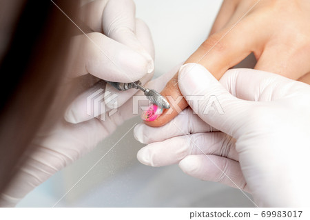 Manicure master uses an electric nail machine Manicure master uses an electric nail machine 69983017