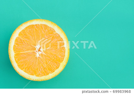 Top view of a one orange fruit slice on bright background in turquoise green color. A saturated citrus texture image Top view of a one orange fruit slice on bright background in turquoise green color. A saturated citrus texture image 69983968