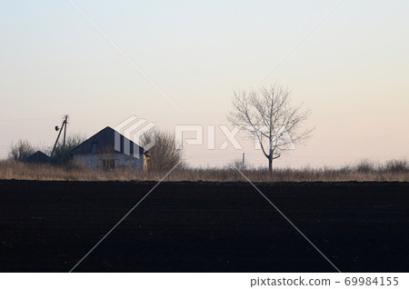 Dawn in the village. A minimalistic photo with a horizon line on which there is an apartment house and a tree Dawn in the village. A minimalistic photo with a horizon line on which there is an apartment house and a tree 69984155
