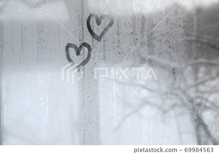 Two hearts painted on a misted glass in winter Two hearts painted on a misted glass in winter 69984563