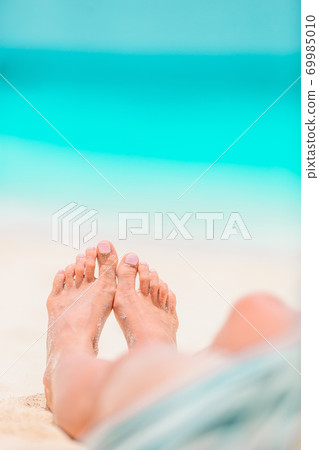 Woman's feet on the white sand beach in shallow water 69985010
