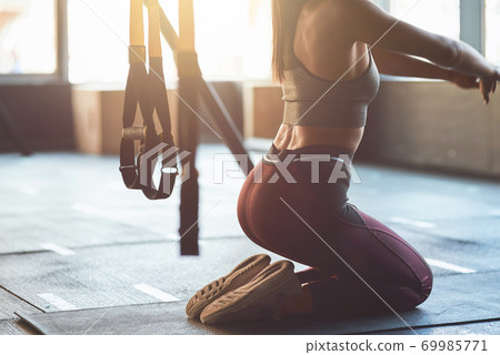 Warming up before workout. Cropped shot of athletic woman in sportswear stretching her body while kneeling down on the floor at gym 69985771