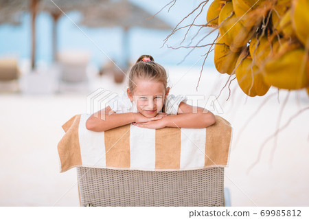 Little adorable girl near coconut on white tropical beach 69985812