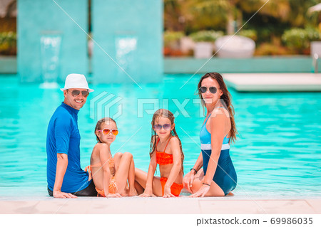 Happy family of four in outdoors swimming pool 69986035