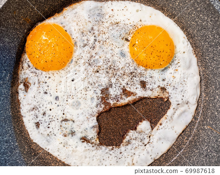 Close-up photo of an unusual fried egg with two yolks similar to an emoticon 69987618