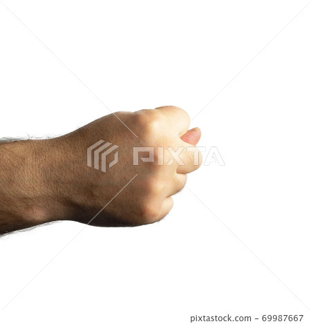 Male brutal hairy hand clenched into a fist and thumb sticks out between the middle and index fingers 69987667