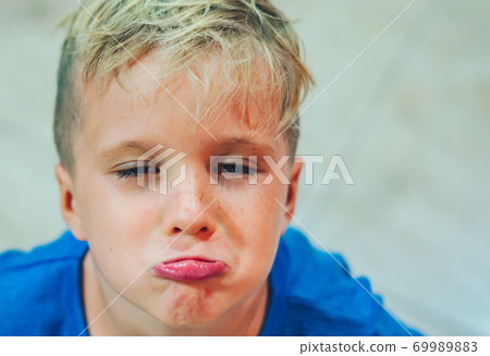 Closeup portrait boy mischievous cute blond close blue eyes, stuck out lip gesture of unwillingness, making freckles face play in mood. Funny photo, happiness lifestyle. Daycare, childhood, behaviour Closeup portrait boy mischievous cute blond close blue eyes, stuck out lip gesture of unwillingness, making freckles face play in mood. Funny photo, happiness lifestyle. Daycare, childhood, behaviour 69989883