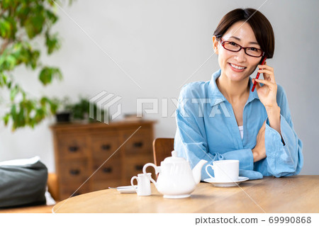 A smiling woman calling in the living room A smiling woman calling in the living room 69990868