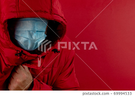 man in red jacket is using a protective mask against corona virus on red background, red color symbol of high alert and stop sign against the disease 69994533