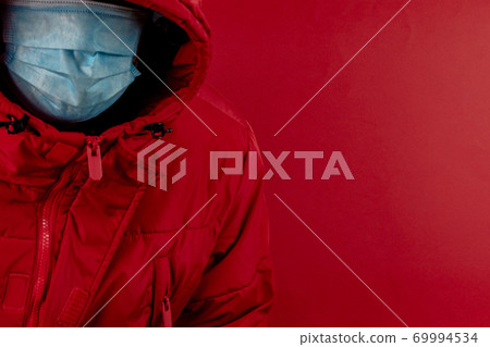 man in red jacket is using a protective mask against corona virus on red background, red color symbol of high alert and stop sign against the disease 69994534