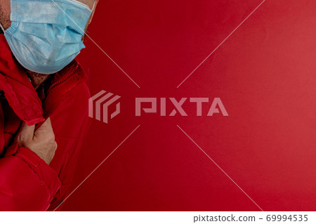 man in red jacket is using a protective mask against corona virus on red background, red color symbol of high alert and stop sign against the disease 69994535