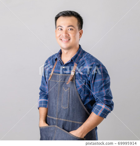 Asian man in barista uniform standing in studio isolated on grey background 69995914