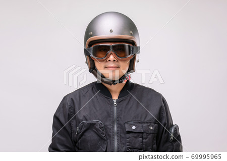 Motorcyclist or rider wearing vintage helmet. Safe ride concept. Studio shot on grey Motorcyclist or rider wearing vintage helmet. Safe ride concept. Studio shot on grey 69995965