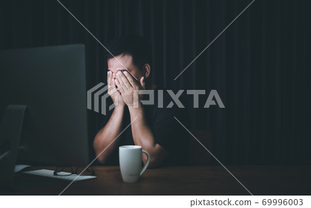 Eyestrain concept. Man touching his eyes because tired after working long time on computer 69996003